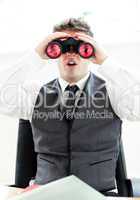 Impressed businessman looking through binoculars sitting in his