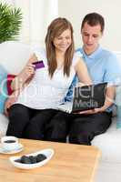 Happy couple using a laptop to buy online