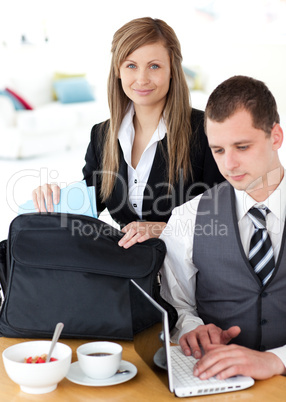Businesswoman packing her bag businessman using laptop