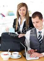 Businesswoman packing her bag businessman using laptop