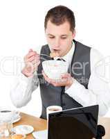 Concentrated businessman eating cereals looking at his laptop