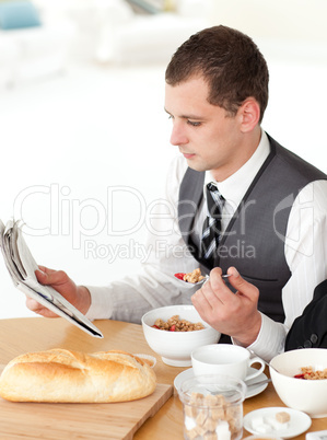 Businessman eating cereals while reading the news