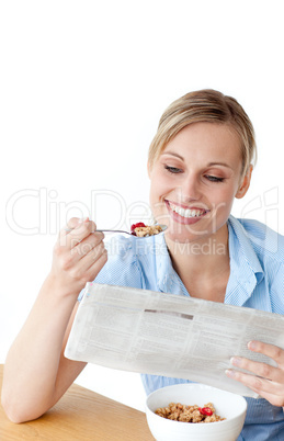 Glowing woman eating cereals while reading newspaper