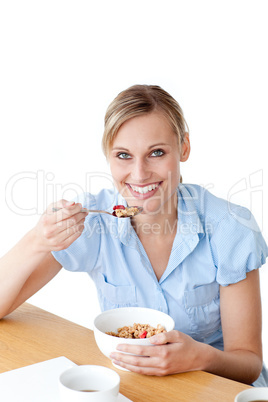 Delilghted woman eating cereals sitting at a table