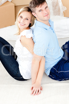 Affectionate young couple sitting on the floor in front of boxes