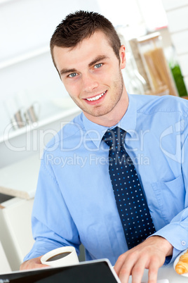 Handsome businessman using a laptop in the kitchen