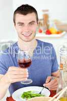Cute man eating a healthy salad with some wine