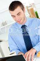Charming businessman using a laptop in the kitchen