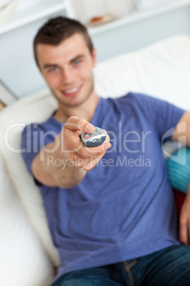 Young man is relaxing in the living-room with remote
