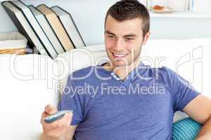 Cute man is relaxing in the living-room with remote