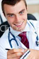 Smiling male doctor writing a perscription