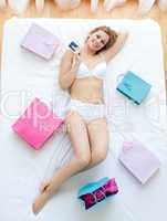 Nice woman lying in bed with shopping bags