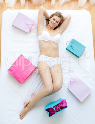Erotic woman lying in bed with shopping bags