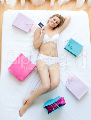 Good-looking woman lying in bed with shopping bags