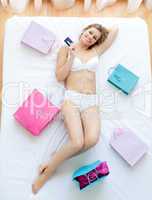 Good-looking woman lying in bed with shopping bags