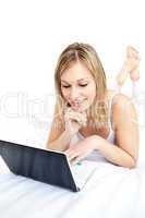 Cute woman lying with a laptop on sofa