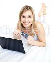 Radiant woman lying with a laptop on sofa
