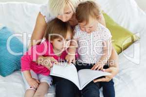 Cute mother reading a book with children