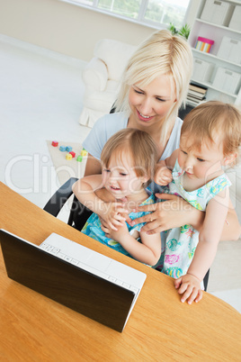 Radiant woman working with her children at laptop