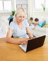 Busy woman working with her children at laptop