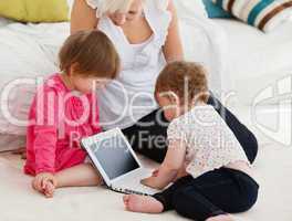 Woman working with her children at laptop