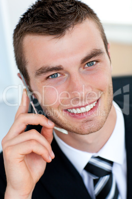 Charming businessman using his mobile phone in office