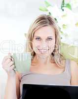 Woman sitting in front of her laptop and holding a cup