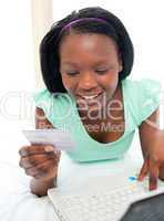 Smiling woman using a laptop sitting on bed