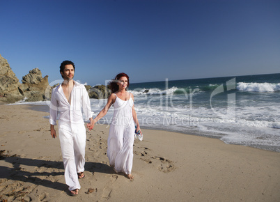 Young Couple at the beach walking while holding hands