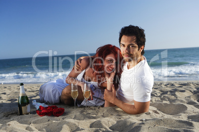 Couple at the beach with champagne and red roses