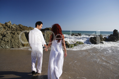Young Couple at the beach holding hands and walking