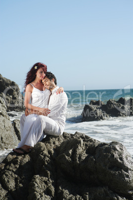 Young couple at the beach sitting on rocks