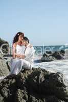 Young couple at the beach sitting on rocks