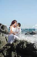 Young couple at the beach sitting on rocks and kissing