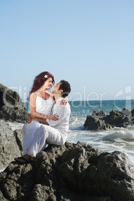 Young couple at the beach sitting on rocks