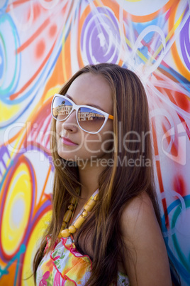 Young woman in glasses near graffiti wall