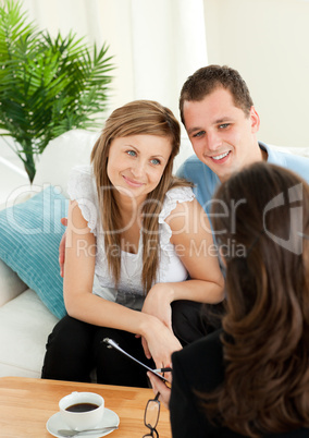Affectionate couple listen to a saleswoman siting on a sofa