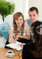 Loving young couple signing a contract sitting in the living roo