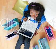 Radiant young teenager sitting on the floor with laptop and shop