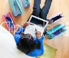 Pretty afro-american teenager using a laptop sitting between sho