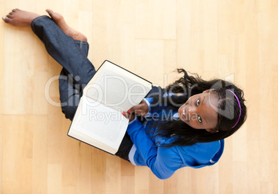 Delighted young woman looking up at the camera holidng a book