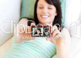 Attractive woman taking a picture of herself lying on bed