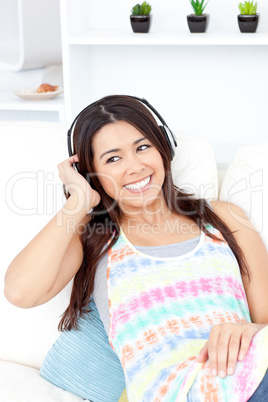 Jolly asian woman with headphones  lying on a sofa