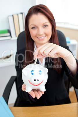Self-assured young businesswoman putting money in a piggybank