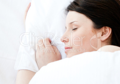 Relaxed young woman lying in a bed sleeping
