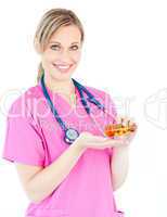 Confident female nurse holding pills smiling at the camera