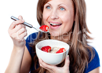 Positive young woman eating cereals with strawberries