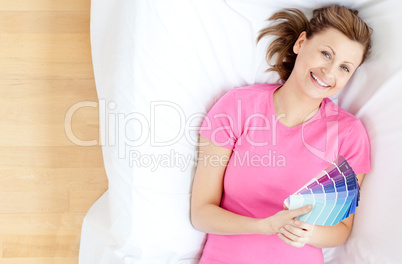 Pretty caucasian woman lying on a sofa holding color sample
