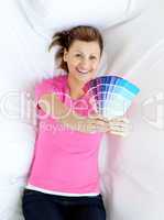 Delighted woman lying on a sofa holding color sample