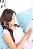 Delighted woman sitting on her sofa reading a book